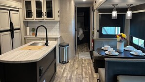 A compact kitchen with a sink, cabinets, and a dining area with a table and chairs. - "Gone Coastal" Luxury Glamper by the Beach (Carrabelle)