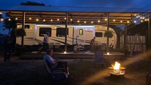 A covered outdoor area with a fire pit, seating, and a recreational vehicle. - "Gone Coastal" Luxury Glamper by the Beach (Carrabelle)