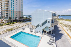 Un edificio moderno con piscina y asientos al aire libre, cerca de una playa y el agua.