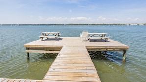 Une jetée en bois s’avançant dans une étendue d’eau calme, avec des tables et des chaises pour pique-niquer.