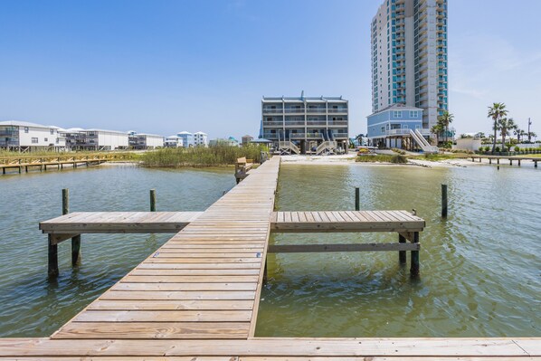 A wooden pier extending into calm water with a building in the background.
