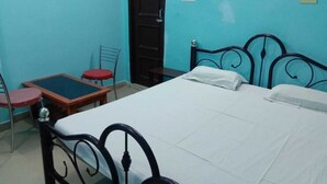 A room with a bed, a table with chairs, and a door. - Janardan Homestay Lucknow (Lucknow)