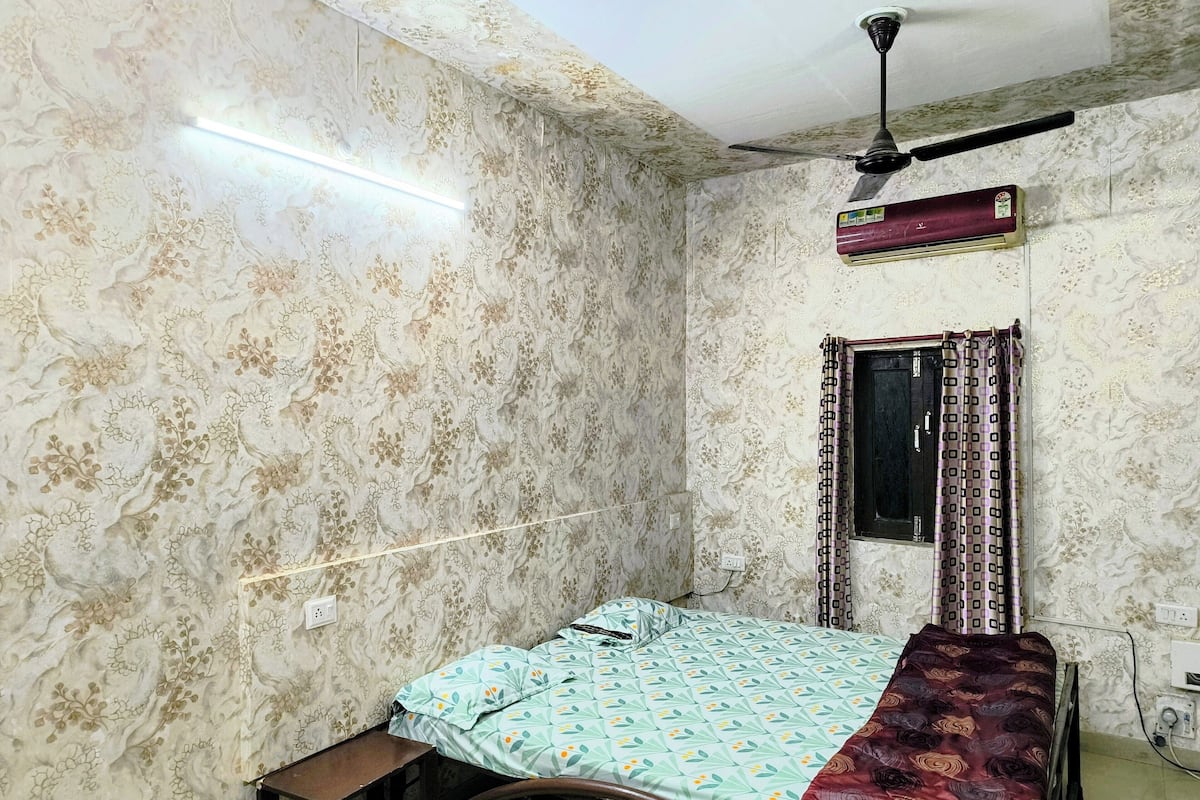 Ein Schlafzimmer mit Bett, Deckenventilator, Klimaanlage und strukturierter Wandgestaltung.
