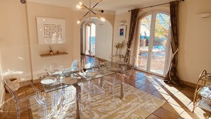 A dining area with a glass table and chairs, a patterned rug, and a view of the outdoors through large sliding doors. - Splendid 6-bedroom villa with sea view in Grasse (Grasse)