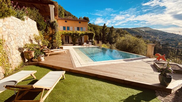 A pool area with a wooden deck, lounge chairs, and a stone wall. - Splendid 6-bedroom villa with sea view in Grasse (Grasse)
