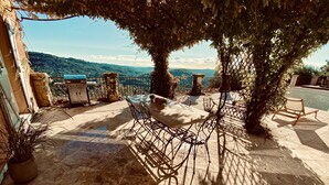 An outdoor seating area with a table and chairs, surrounded by potted plants and trees, overlooking a scenic view. - Splendid 6-bedroom villa with sea view in Grasse (Grasse)