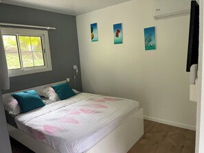 Een slaapkamer met een bed, een raam en drie foto’s aan de muur.