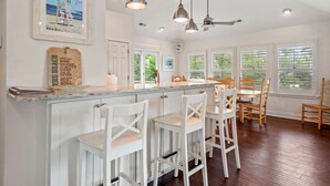 A spacious kitchen with a central island, white cabinetry, and bar stools. - Hidden Gem: Private Pool | Hot Tub | Tiki Bar (Corolla)