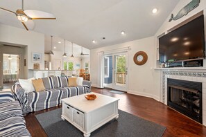 A spacious living room with a large TV, a fireplace, and a dining area with a view. - Hidden Gem: Private Pool | Hot Tub | Tiki Bar (Corolla)