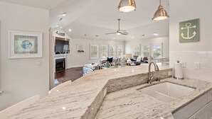 A spacious kitchen with a large island, modern pendant lights, and a view into the living area. - Hidden Gem: Private Pool | Hot Tub | Tiki Bar (Corolla)