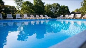 Une piscine avec des chaises longues blanches et une clôture.