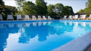 Une piscine avec des chaises longues blanches et une clôture.