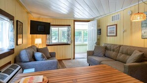 Ett mysigt vardagsrum med två soffor, ett träbord och en tv som är monterad på väggen.