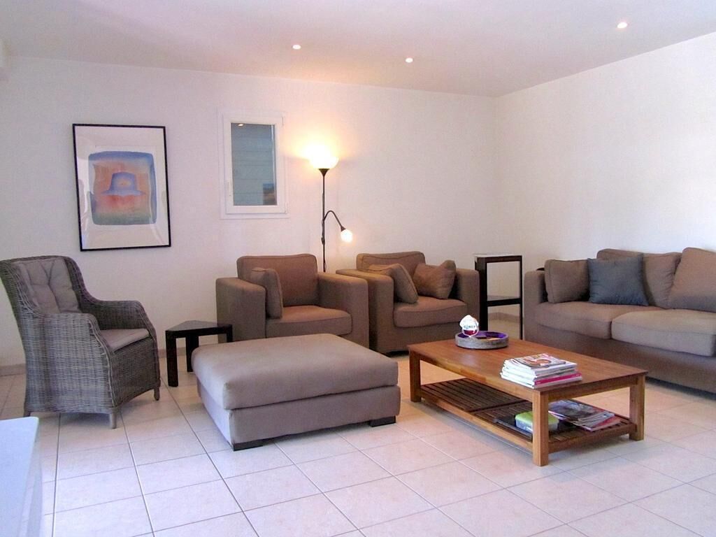 A modern living room with a grey armchair, two sofas, a coffee table, and a floor lamp.