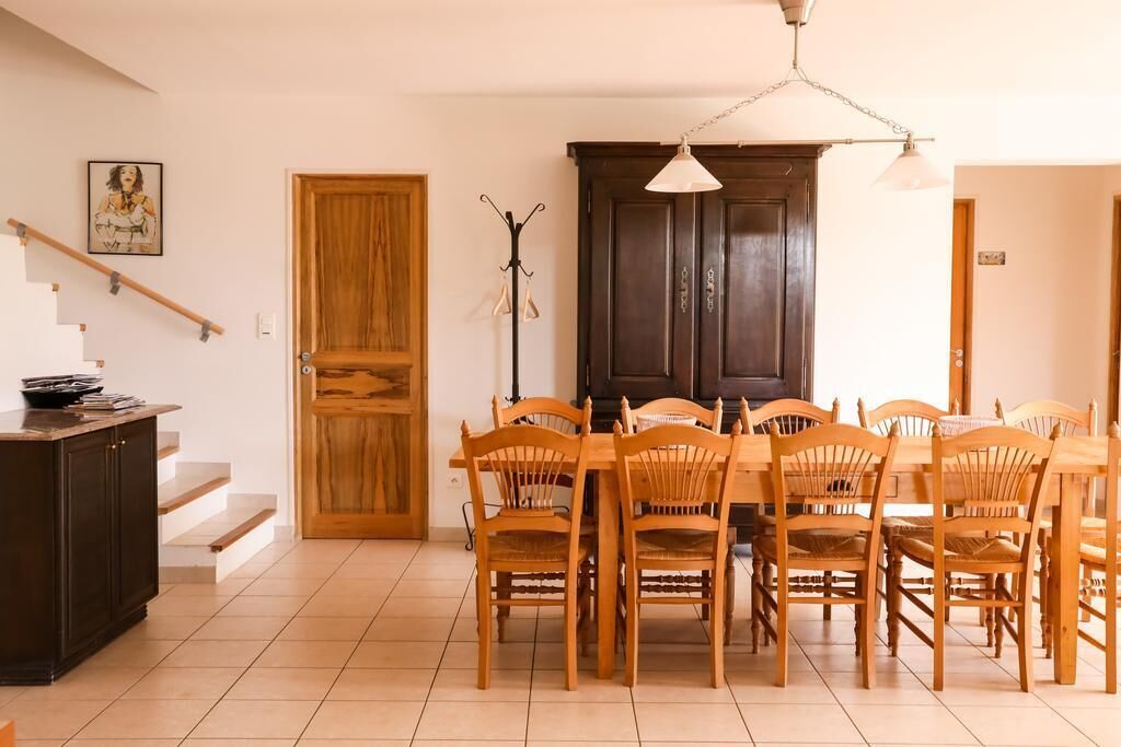 Een eetgedeelte met een houten tafel en stoelen, een kapstok en een trap.