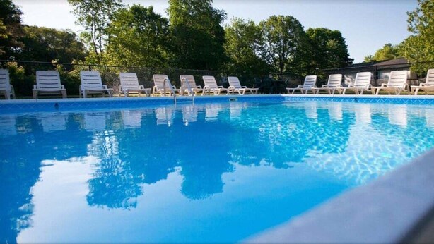 Ein Swimmingpool mit weißen Liegestühlen und einem Zaun.