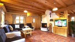 A cozy log cabin interior with a fireplace, wooden furniture, and a television.
