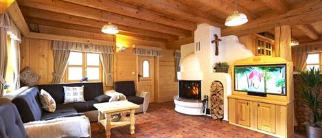 Interior acogedor de una cabaña de troncos con chimenea, muebles de madera y un televisor.