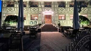 Ein traditionelles Gebäude mit einem Restaurant namens "Fachwerk" am Eingang, Außenbestuhlung mit Tischen und Stühlen sowie ein Ziegelweg, der zum Eingang führt.