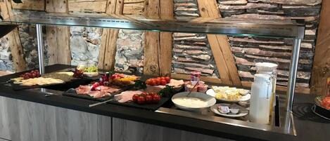 A buffet with various food items including meats, cheeses, and fruits.