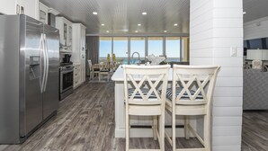 Una cucina moderna con elettrodomestici in acciaio inossidabile, pavimento in legno e vista sull'oceano.