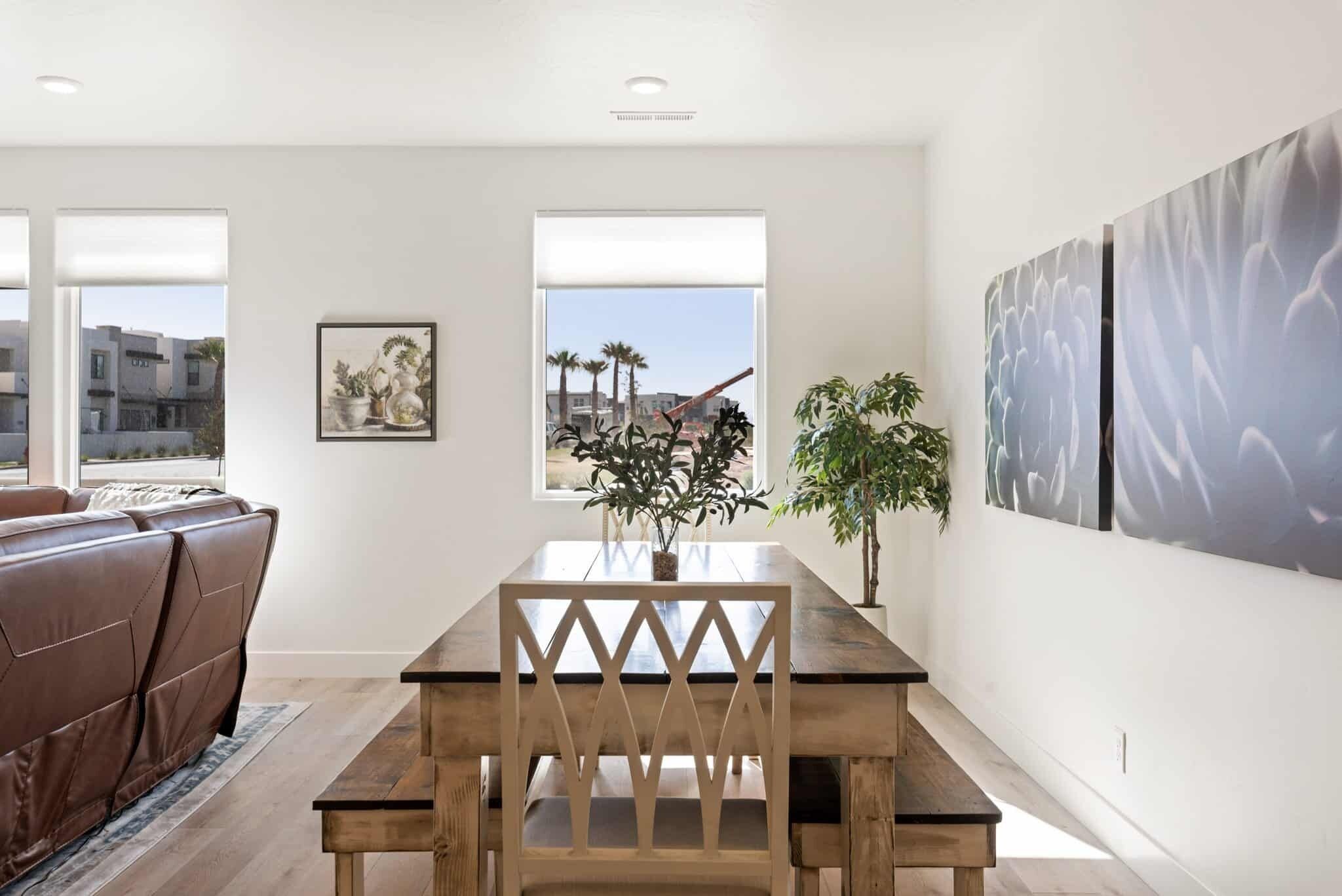 Een moderne eetruimte met een houten tafel en stoelen, een potplant en een uitzicht op de stad door grote ramen.