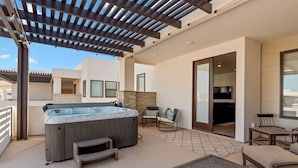 A covered outdoor patio with a hot tub, seating area, and a stone fireplace. - Cloud 9 At Desert Color: Desert Color Lagoon + Beaches (St. George)