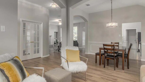 A spacious living room with a dining area, wooden flooring, and a chandelier. - Frisco Spacious & Cozy Bling Home by Aya (Frisco)