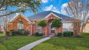 A brick house with a front entrance, a covered porch, and a well-maintained lawn. - Frisco Spacious & Cozy Bling Home by Aya (Frisco)