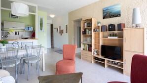 Un salon moderne comprenant un coin repas, un téléviseur et une bibliothèque.