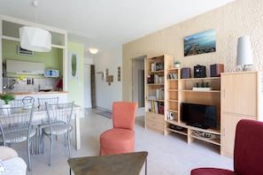 A modern living room with a dining area, a television, and a bookshelf.