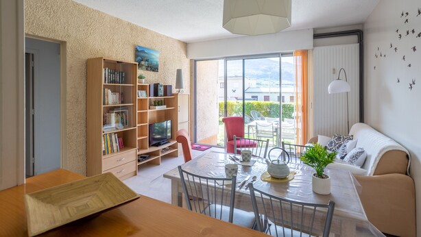 Un salon moderne comprenant un coin repas, une bibliothèque et une vue sur l’extérieur.