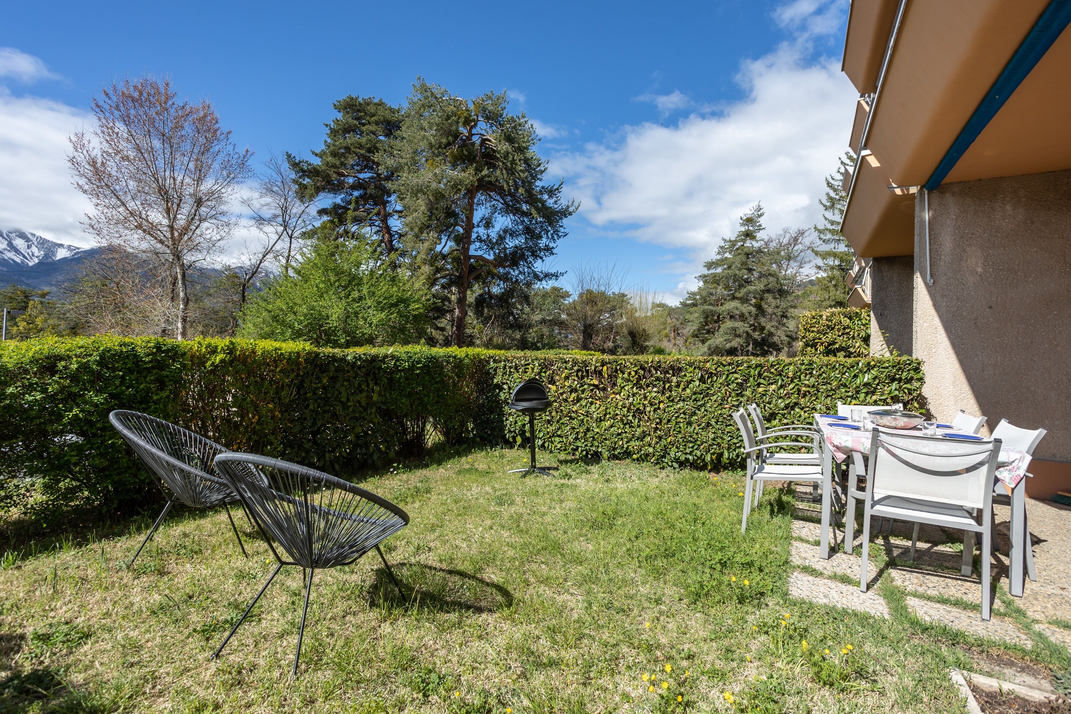 Une terrasse avec des sièges extérieurs, une boîte aux lettres et une haie.
