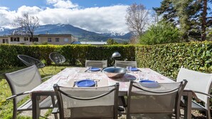 Un espace de restauration en plein air avec une table dressée pour six personnes, entourée de chaises, et une vue sur les montagnes en arrière-plan.