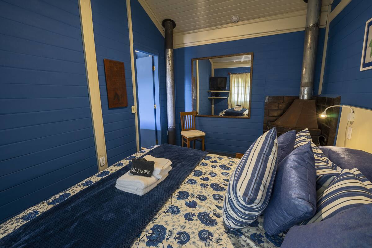 Ein Schlafzimmer mit Bett, Sessel, Spiegel und Kamin.