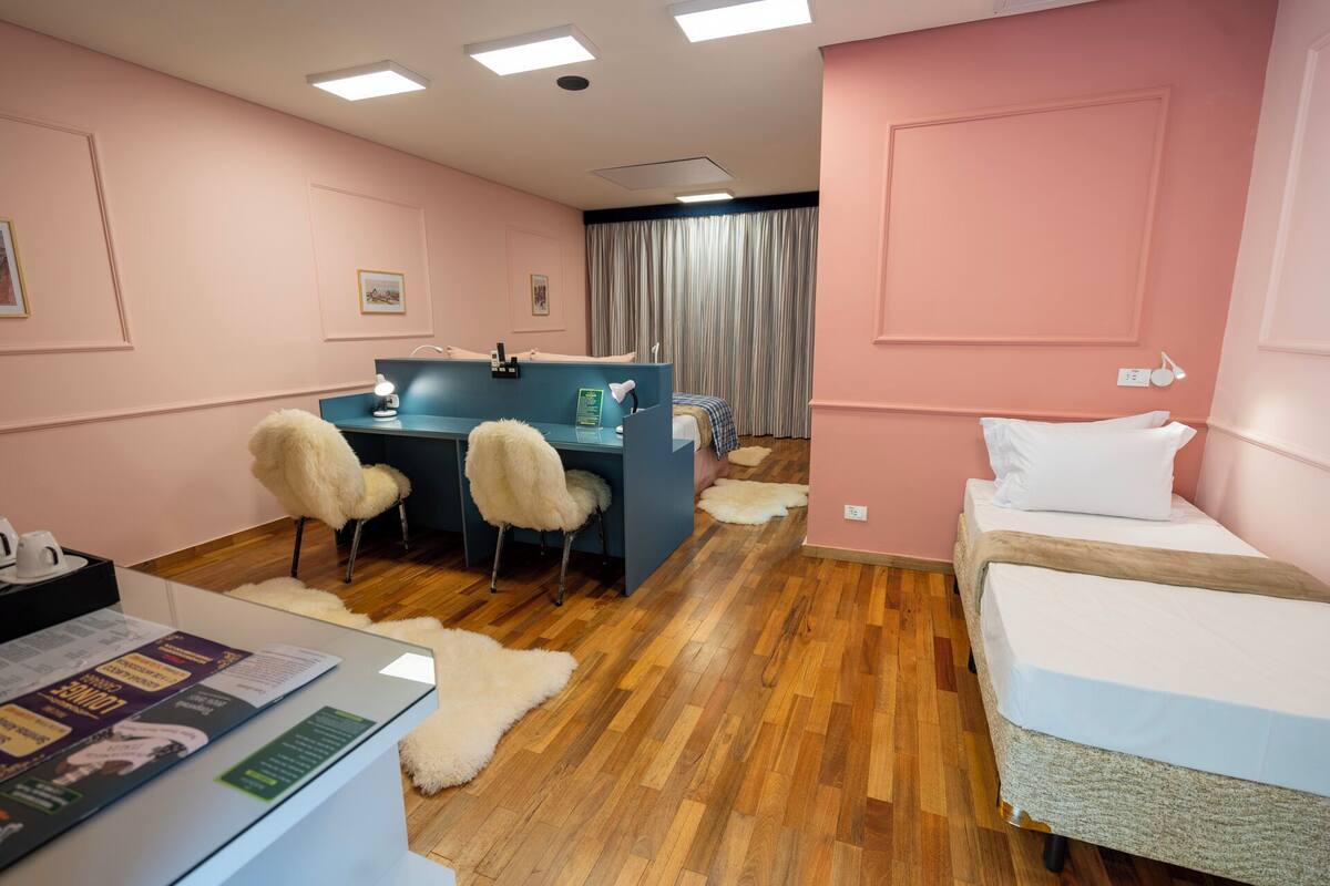 Ein Hotelzimmer mit Schreibtisch, zwei Stühlen, einem Bett und einem Fellteppich.
