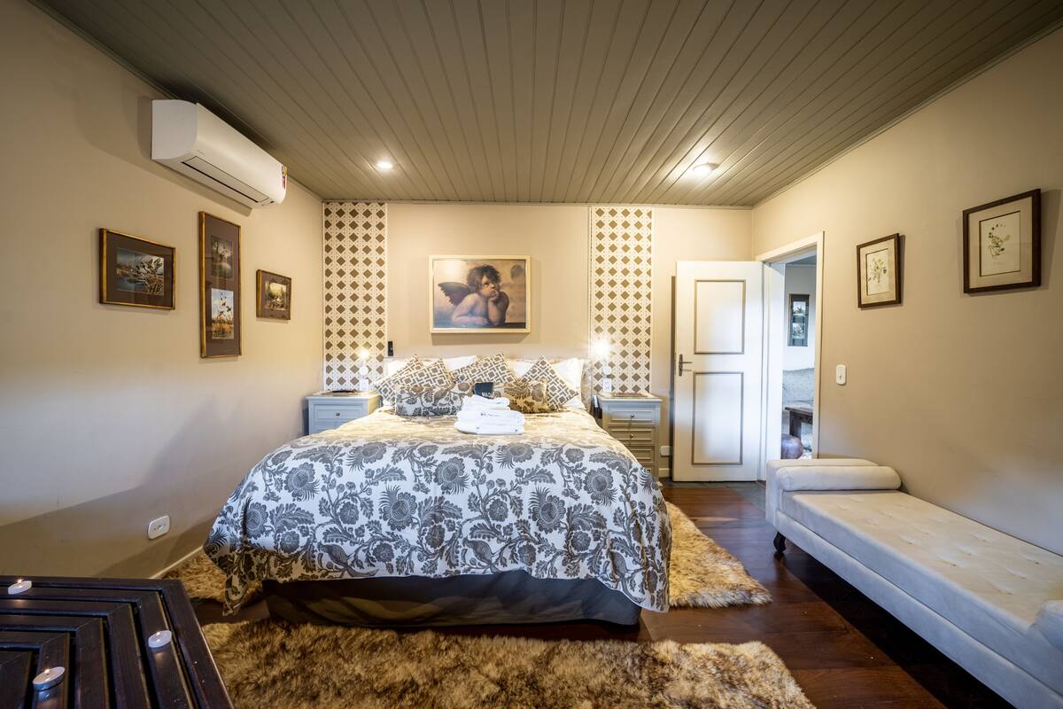 Ein Schlafzimmer mit einem großen Bett, einem Nachttisch, einem Fluschteppich und einer Wand-Klimaanlage.