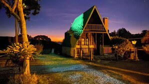 Een huis met een groen dak, een veranda en een stenen schoorsteen.