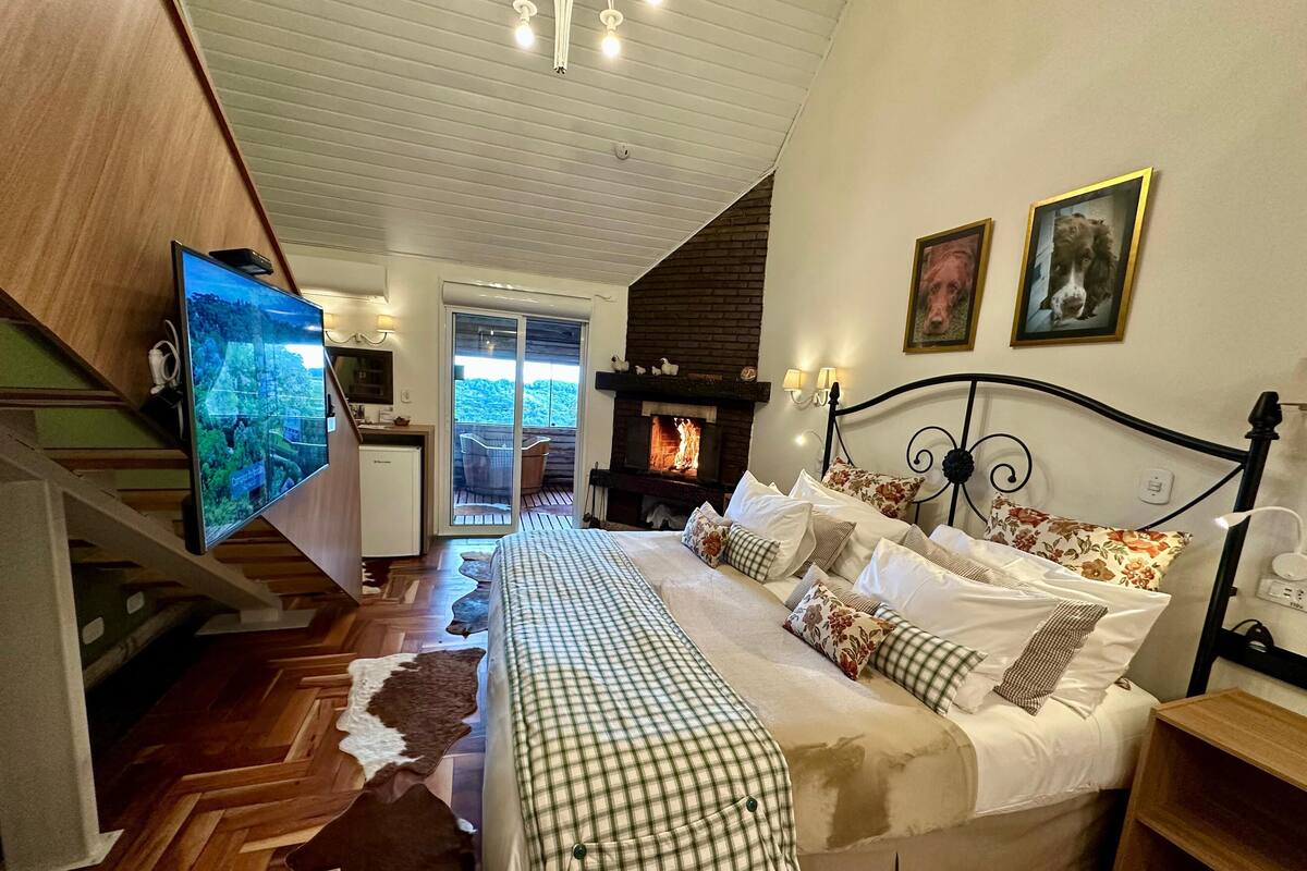 Ein Schlafzimmer mit einem großen Bett, einem Fernseher, einem Kamin und Blick ins Freie.