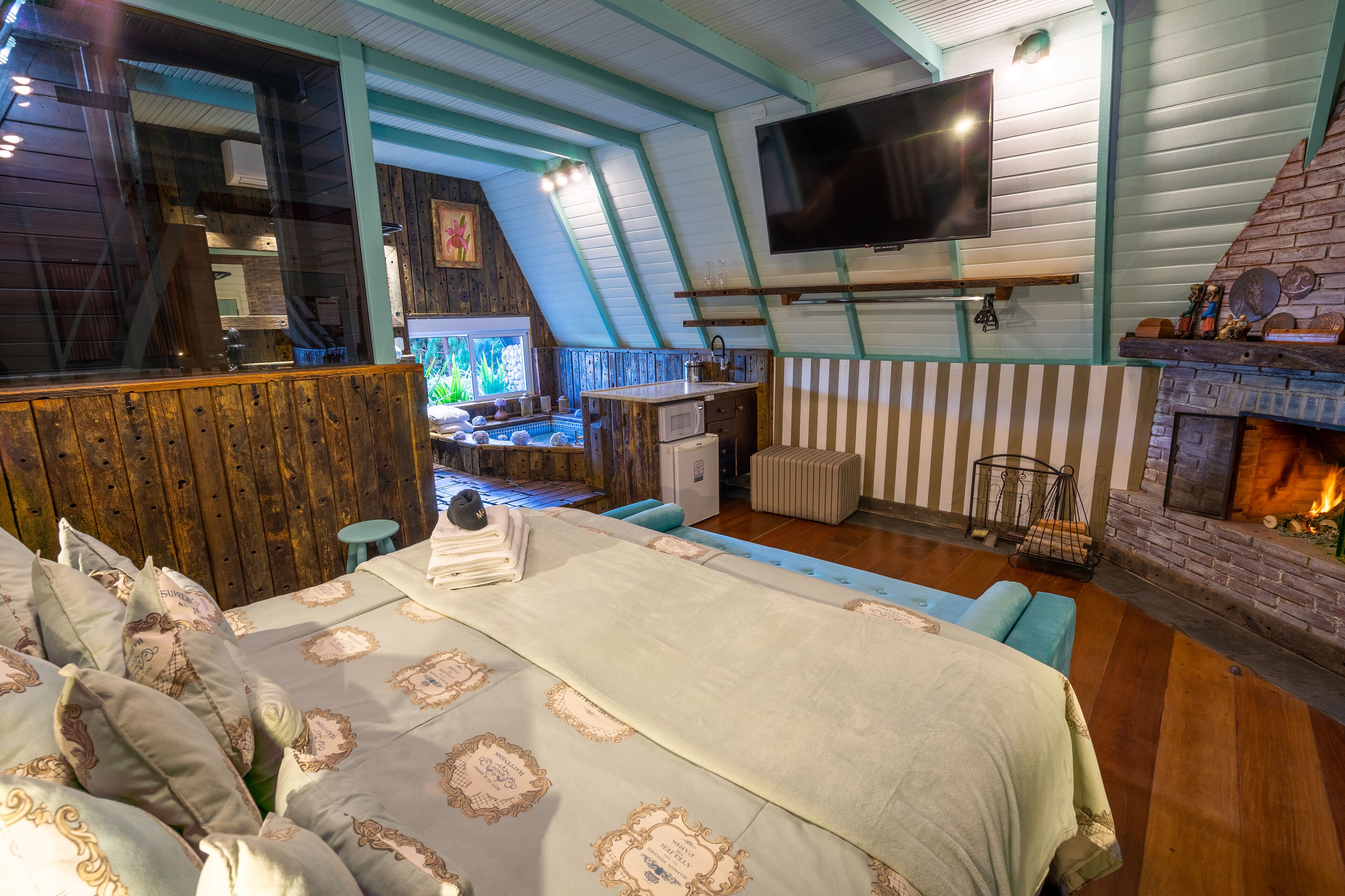Una habitación acogedora con cama, chimenea, televisión y vistas al exterior.