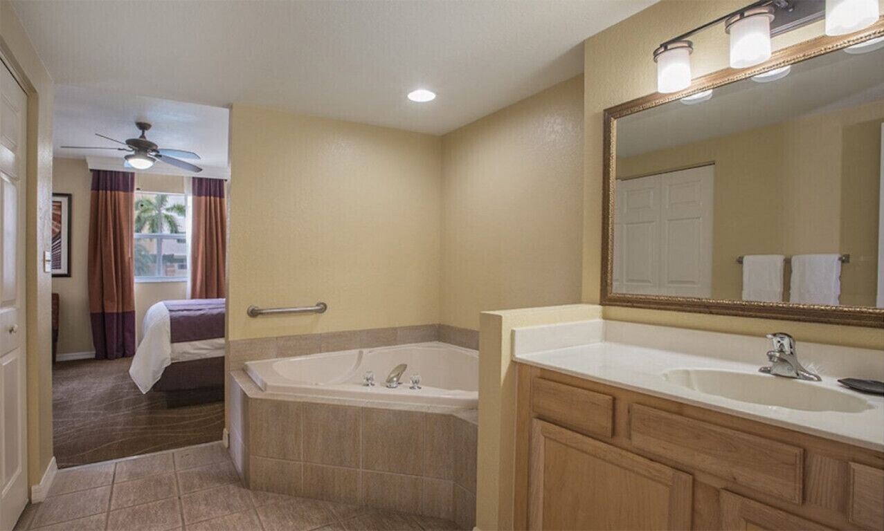 Une salle de bain d’hôtel avec une baignoire, un grand miroir et un meuble-lavabo avec un évier.