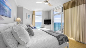 A bedroom with a bed, a ceiling fan, a TV, and a view of the ocean. - Jade East Towers~Beach Front w/Amazing Unparalleled  Sunrise and Sunset Views (Jade East Towers , Destin)