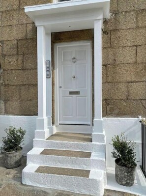 Stunning stone entrance with a welcoming white door and lush greenery.