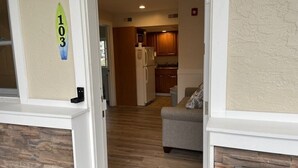 A hallway leading to a kitchen with wooden cabinets and a refrigerator. - Beach block Wildwood Crest ground level condo-103 (Wildwood Crest)