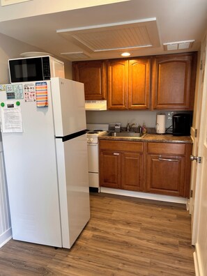 A kitchen with wooden cabinets, a white refrigerator, a stove, and a coffee maker.