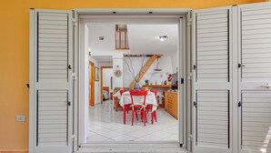 Una stanza con un tavolo da pranzo e sedie, un angolo cottura con mobili in legno e una scala che conduce a un livello superiore.