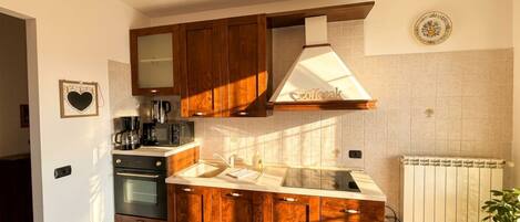A kitchen with wooden cabinets, a coffee maker, and a radiator.