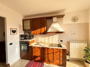 Een keuken met houten kastjes, een koffiezetapparaat en een radiator.