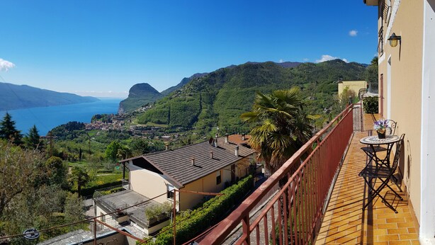 Un balcón con vista a un paisaje costero, que incluye una masa de agua y colinas verdes.