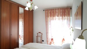 Un dormitorio con una cama grande, un armario de madera y una lámpara colgante.